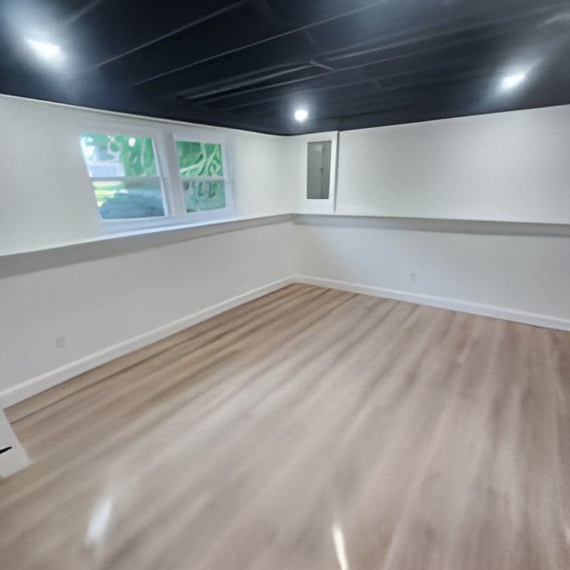 Finished basement room with high windows and vinyl flooring