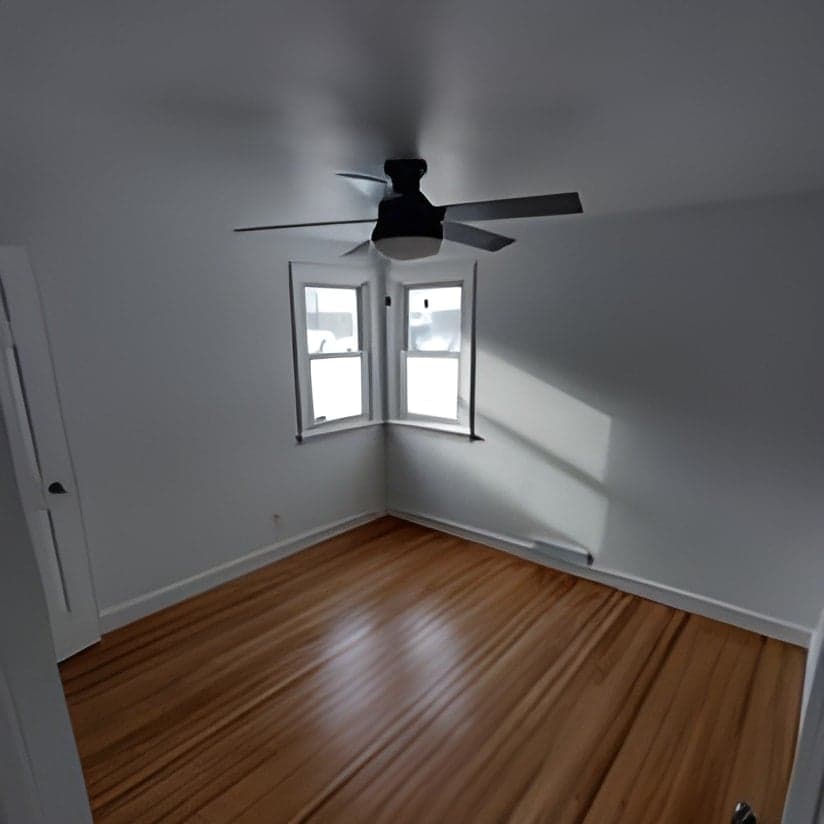 Finished interior room with hardwood floors, ceiling fan, and large window