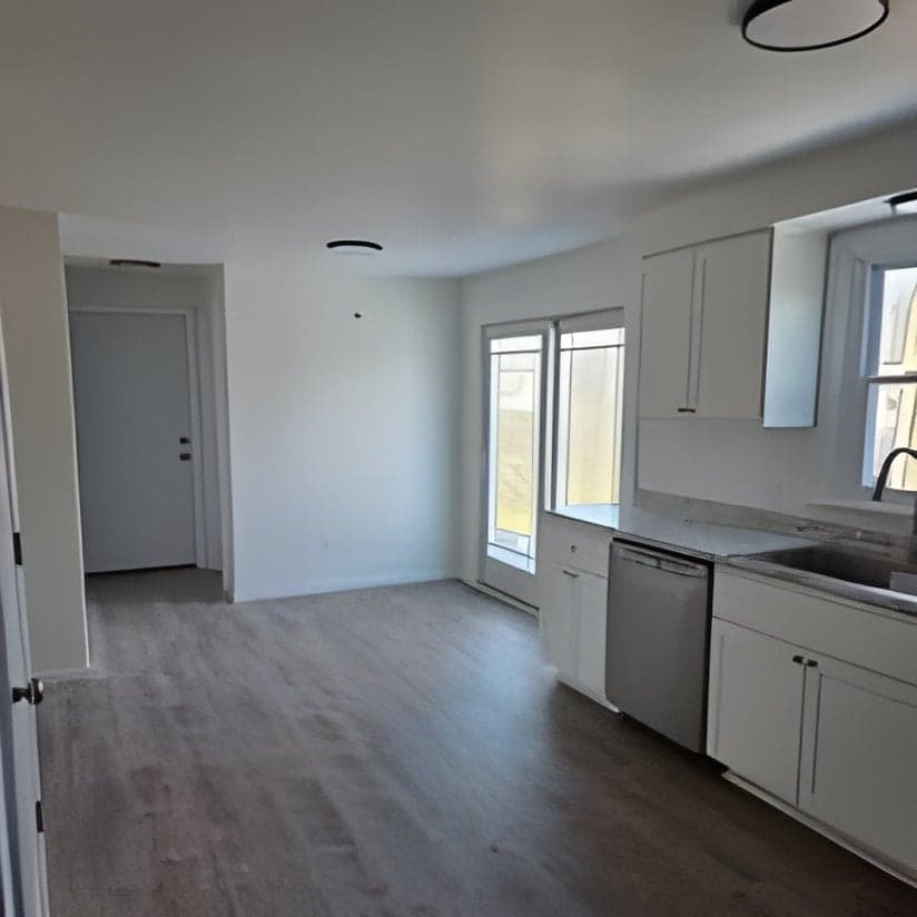 Finished kitchen with white cabinets and wood flooring