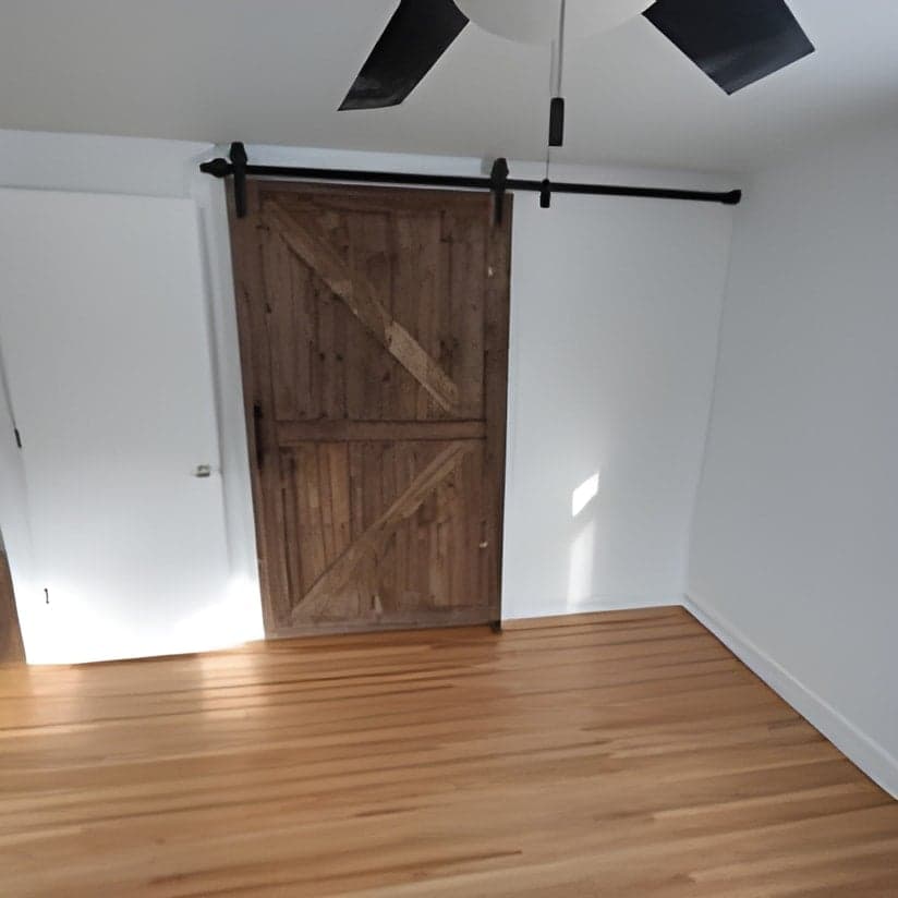 Finished room with sliding barn door and hardwood flooring